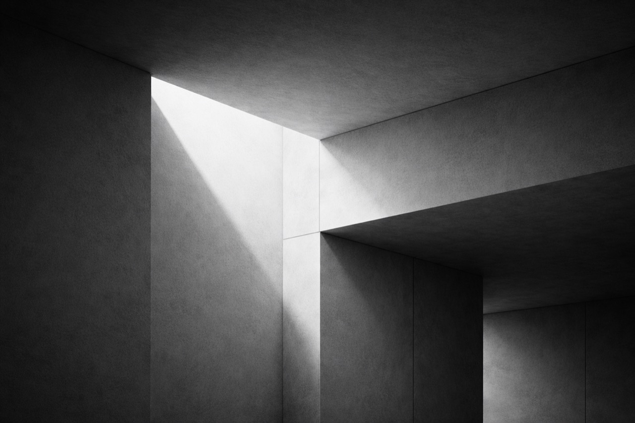 High-contrast monochrome architectural interior with concrete planes and a sharp wedge of overhead light.